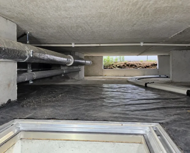 Exposed pipes and a crawl space access hatch beneath a UAE villa show the hidden side of renovation.